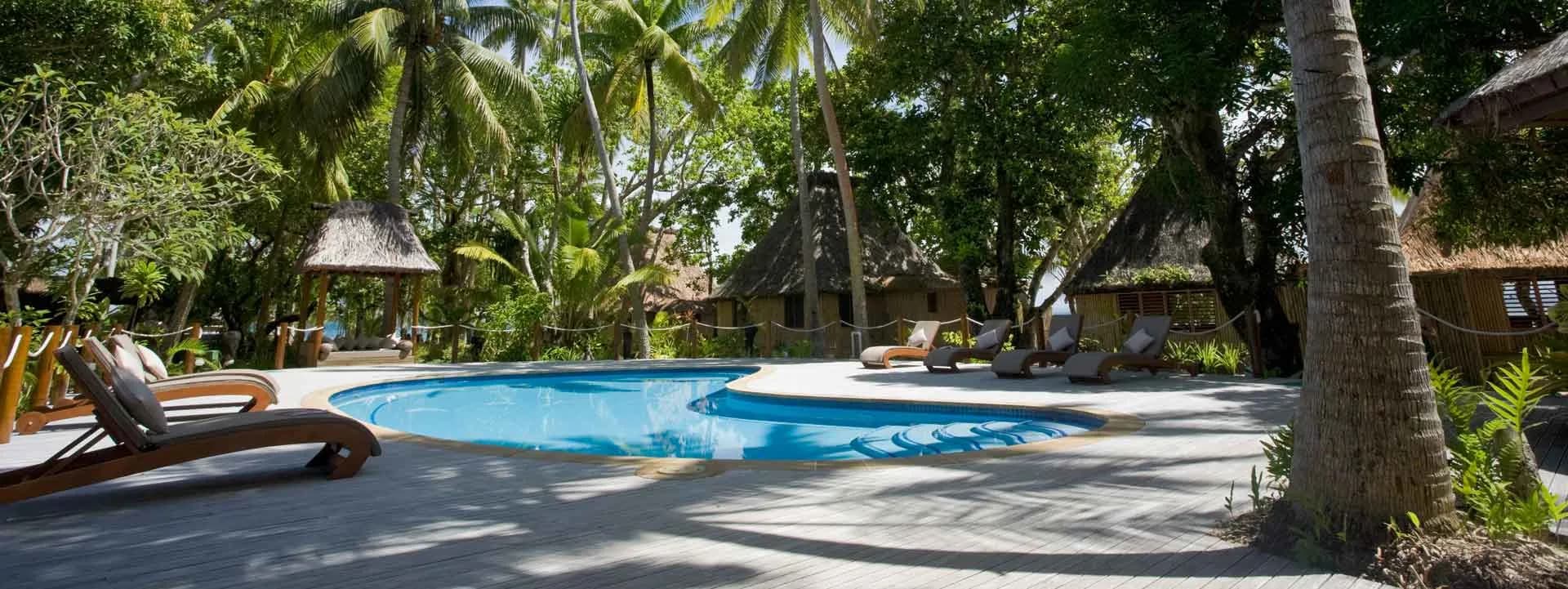 A swimming pool with lounge chairs at Toberua Island Resort Fiji. A swimming pool with lounge chairs at Toberua Island Resort Fiji.