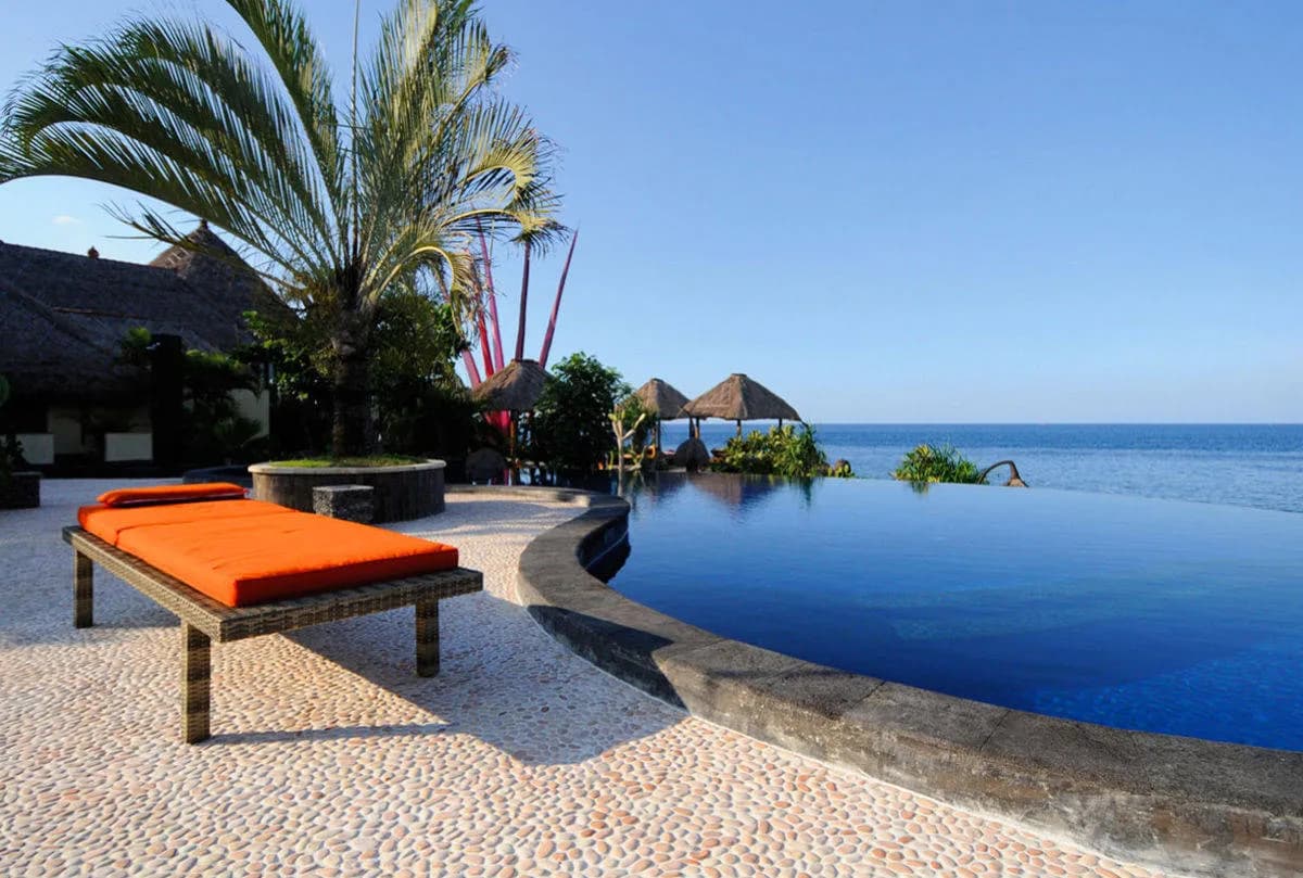 A lounge chair next to the infinity pool looking over the ocean at Alam Batu Beach Bungalow Resort Bali A lounge chair next to the infinity pool looking over the ocean at Alam Batu Beach Bungalow Resort Bali