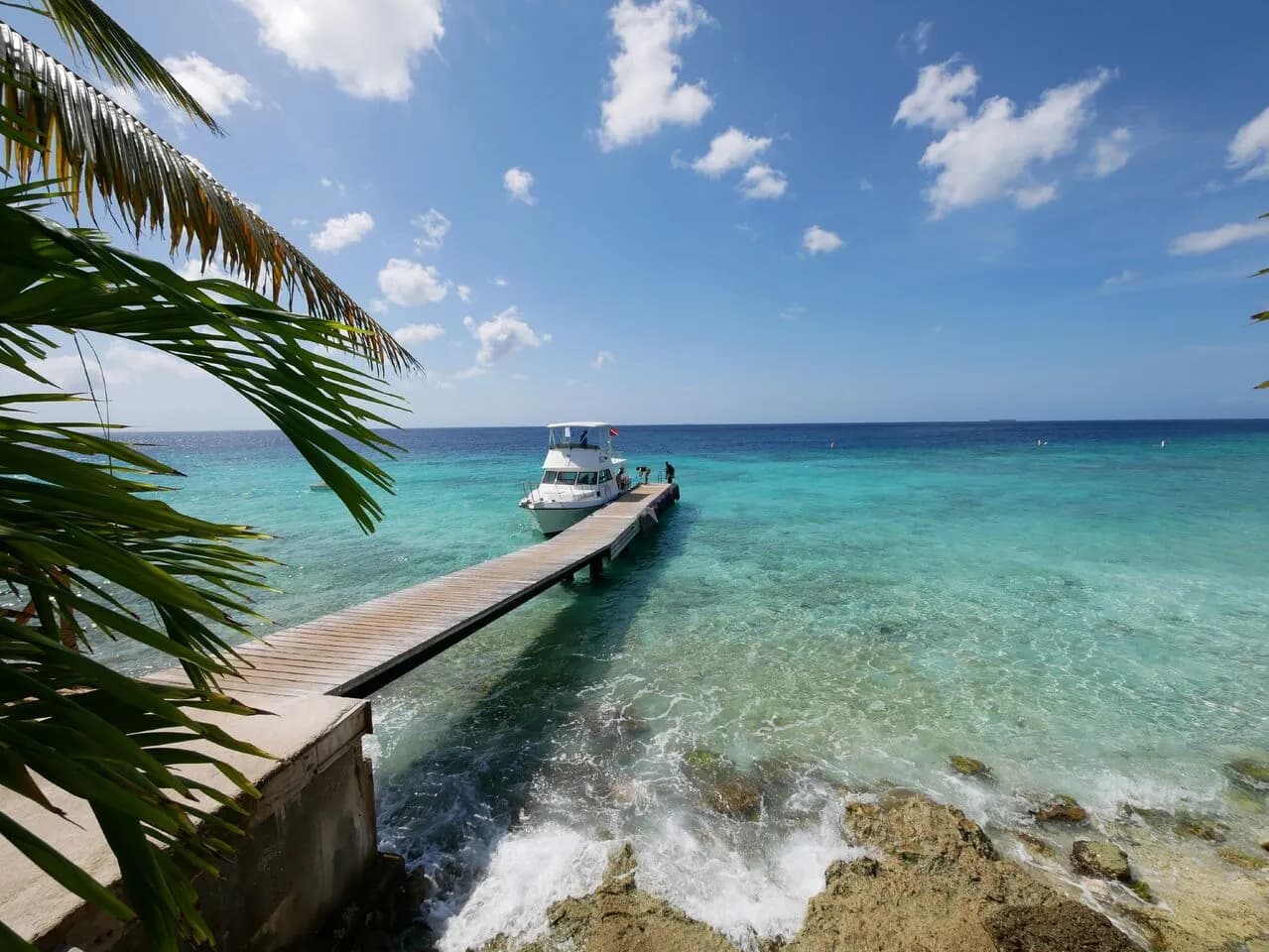 A boat docked on a pier in the ocean, surrounded by calm waters and a picturesque view of the horizon. A boat docked on a pier in the ocean, surrounded by calm waters and a picturesque view of the horizon.