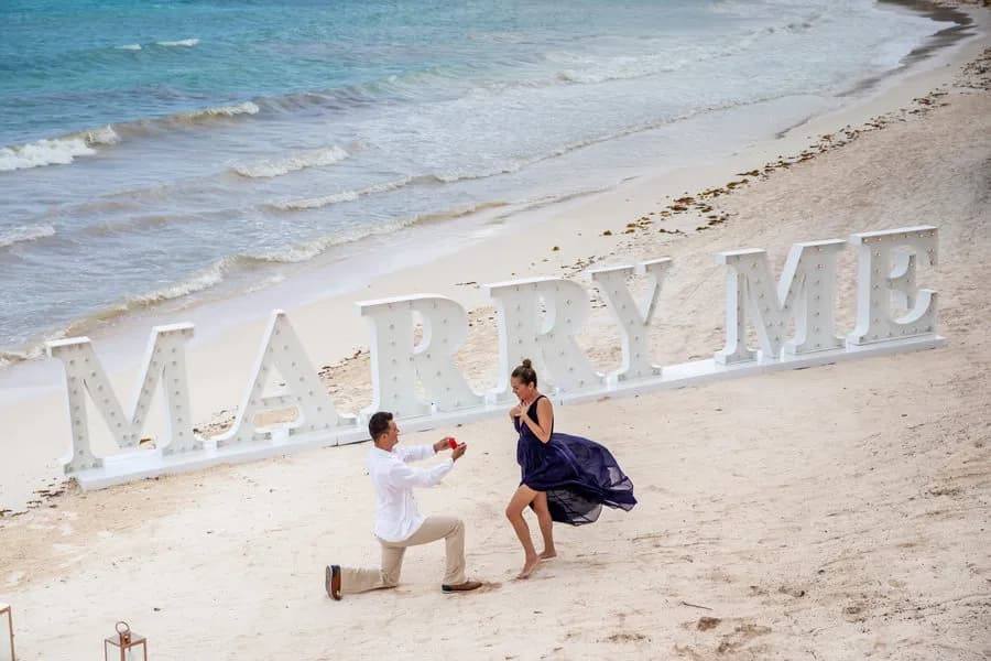 A person proposes marriage to another person on the beach at Barcelo Maya Grand A person proposes marriage to another person on the beach at Barcelo Maya Grand