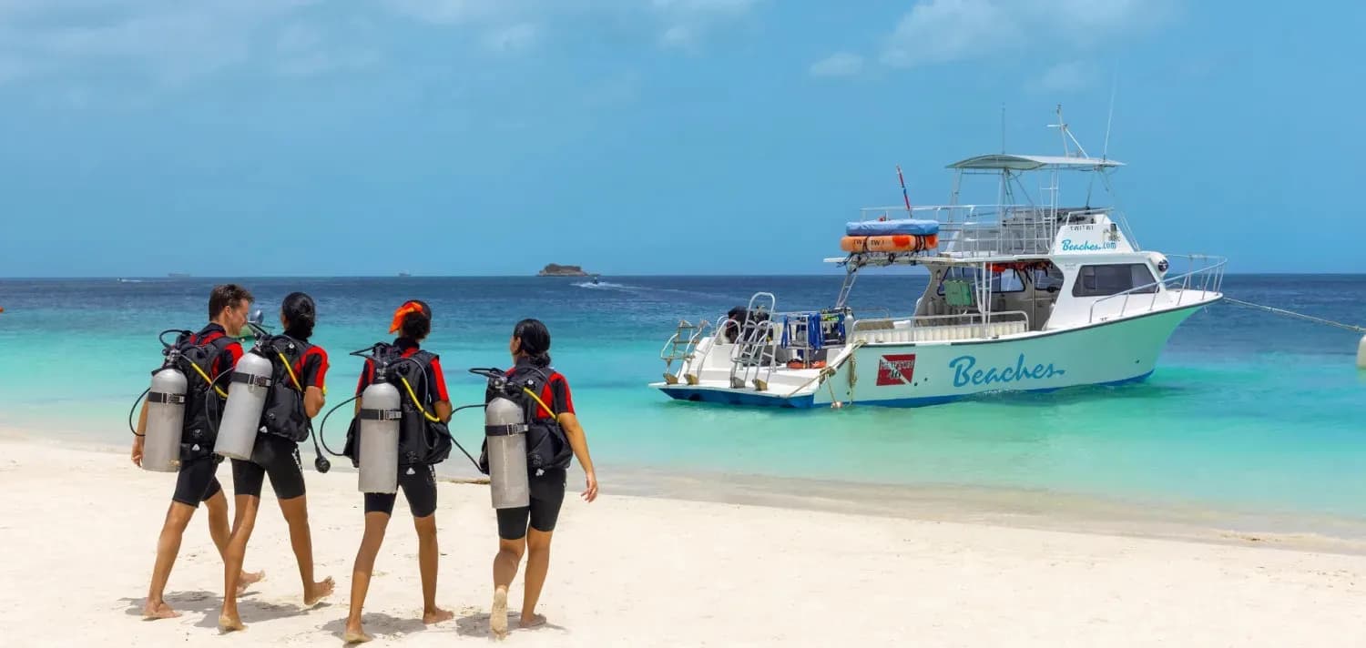 Divers walk on the sand toward the Beaches dive boat Divers walk on the sand toward the Beaches dive boat