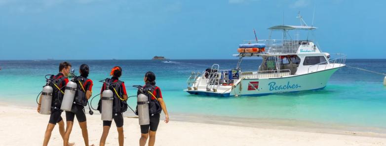 Divers walk on the sand toward the Beaches dive boat