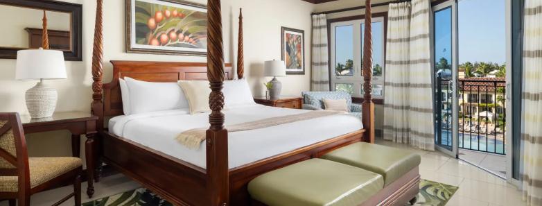 Comfortable bed with balcony overlooking the pool for the Concierge Suites