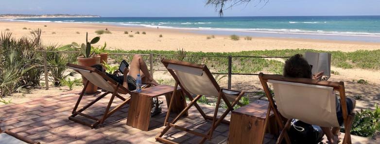 Guests lounge in chairs in front of the beach