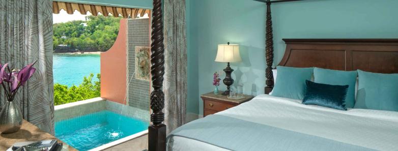 A king bed with a clear blue pool on the veranda