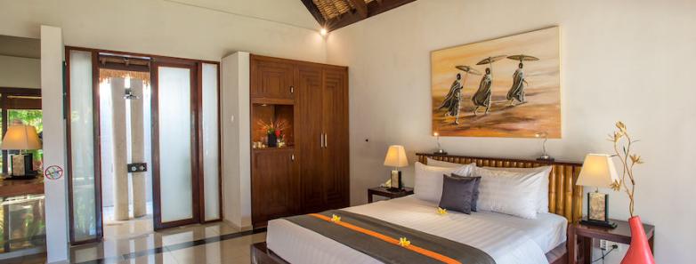 Large bed and Balinese furniture in the Deluxe Bungalow