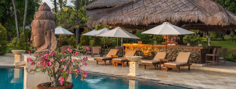 Pool with Balinese decor and sun beds around it