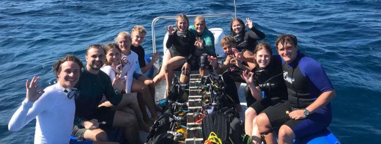 A group of divers backroll into the water